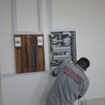 Best Volt electrician terminating an open distribution board beside a timber meter board in a Singapore commercial unit.