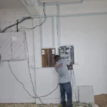 Wide view of cable coils pulled to an open distribution board by Best Volt, trunking already fixed on the commercial-unit wall.