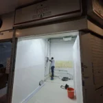 View from under the Audanis Bakes sign into unit 01-07, still a white shell, with Best Volt working a wall point during the fit-out.
