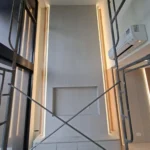 Feature wall by Best Volt in a double-volume Singapore condominium, recessed niche, vertical LED cove on both sides, and a low cabinet below.