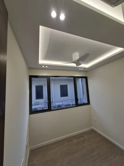 Finished bedroom cove ceiling by Best Volt, with a ceiling fan, downlights, and a three-panel window in a Singapore condominium.