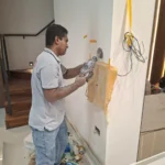 Close-up of wall chasing by Best Volt, dust, a paper catch, tape, and a cable bundle beside the cut in a private residence.
