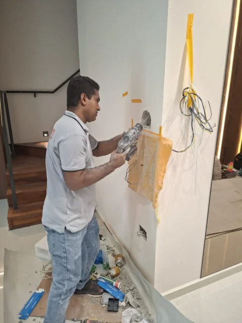 Close-up of wall chasing by Best Volt, dust, a paper catch, tape, and a cable bundle beside the cut in a private residence.