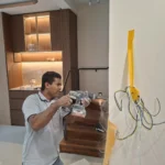 Rotary hammer cutting a chase, staircase and lit kitchen cabinets behind, during concealed wiring by Best Volt.