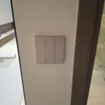 Three-gang smart switch with a blue indicator on each gang, the finished result of concealed wiring and chasing by Best Volt.