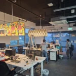 Evening wide view of the same office floor, two pendants, a cassette air-con, and a green EXIT sign, during a Best Volt lighting fit-out.